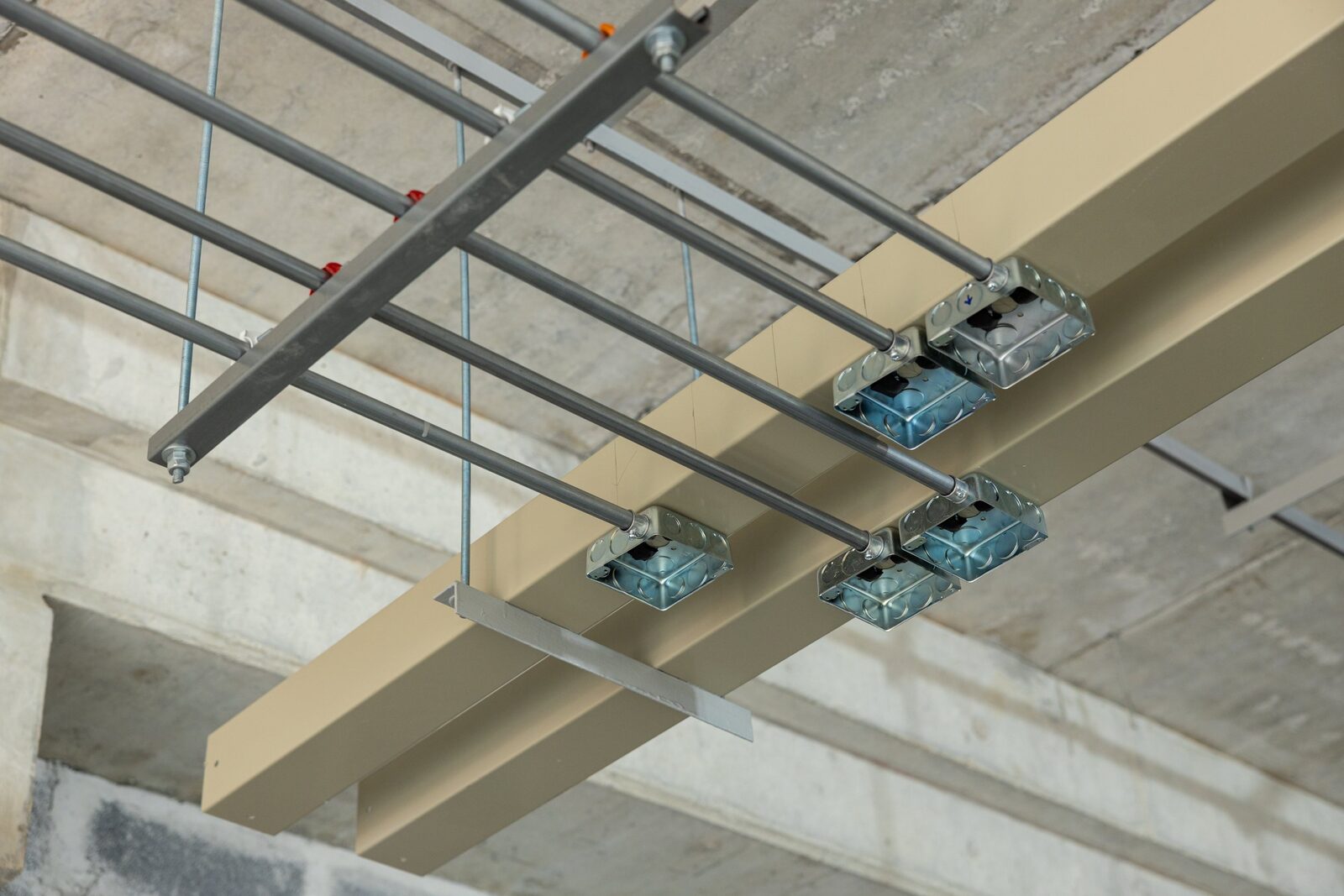 Ceiling installation with metal scaffolding, electrical boxes, and a beige beam.